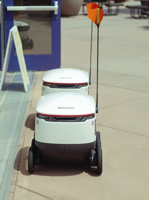 High angle view of two autonomous delivery robots positioned outdoors, showcasing modern technology.