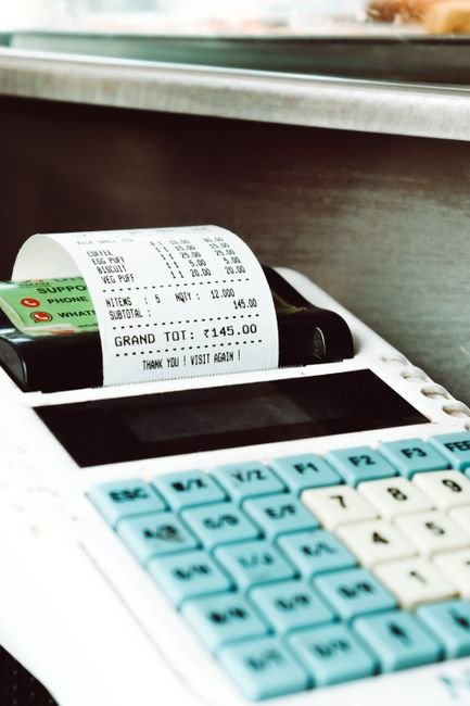 Close-up shot of a cash register printing a receipt with a card nearby, in a retail store.