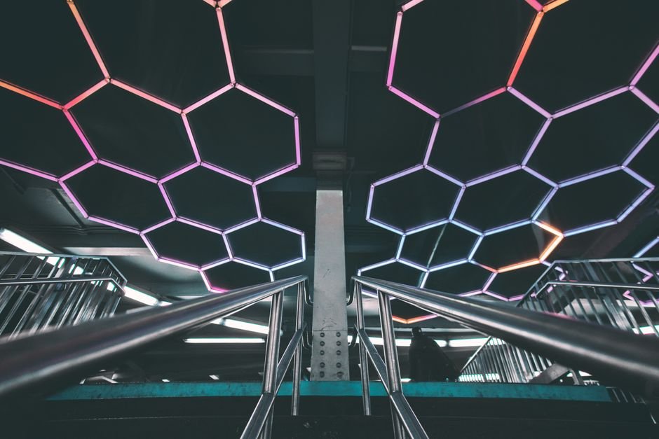 Explore a modern subway station with a futuristic design featuring illuminated geometric patterns and stainless steel railings.