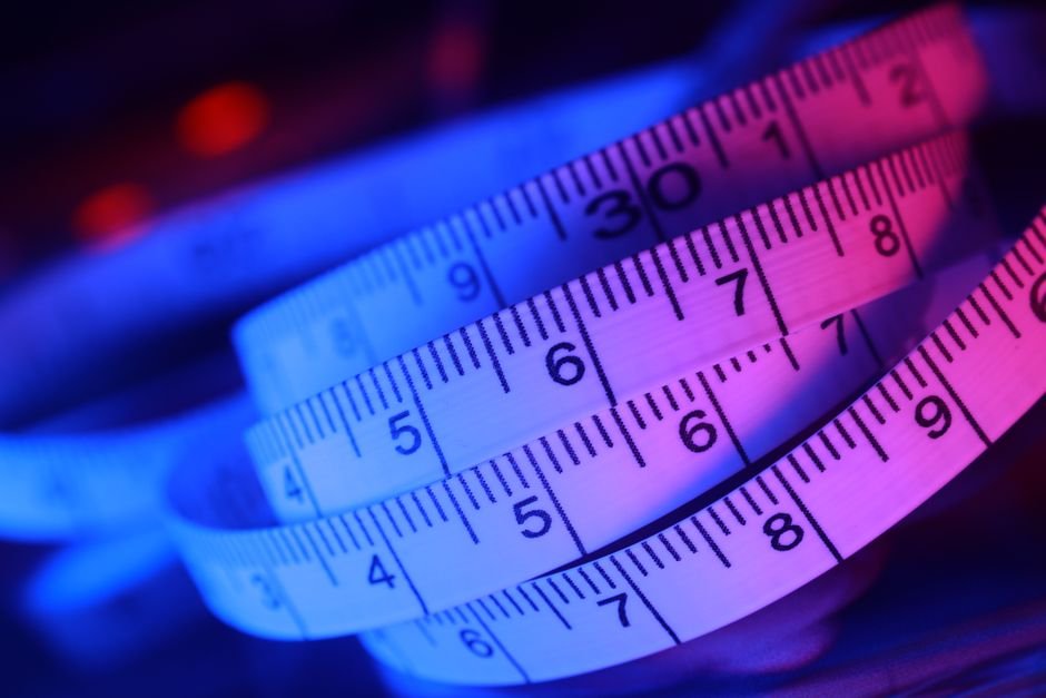Abstract close-up of a measuring tape in vibrant blue and pink lighting.