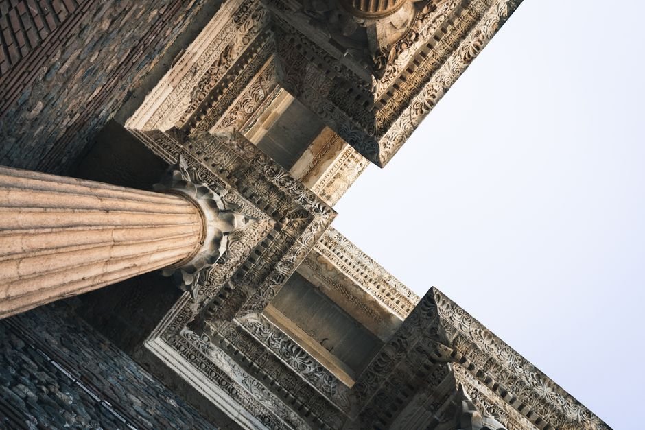 A close-up angular perspective of ornately carved ancient architectural columns with intricate detailing.