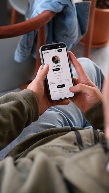 Close-up of a man's hands using a social media app on a smartphone indoors.