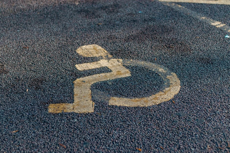 Close-up of a weathered handicap sign painted on a pavement, emphasizing accessibility.