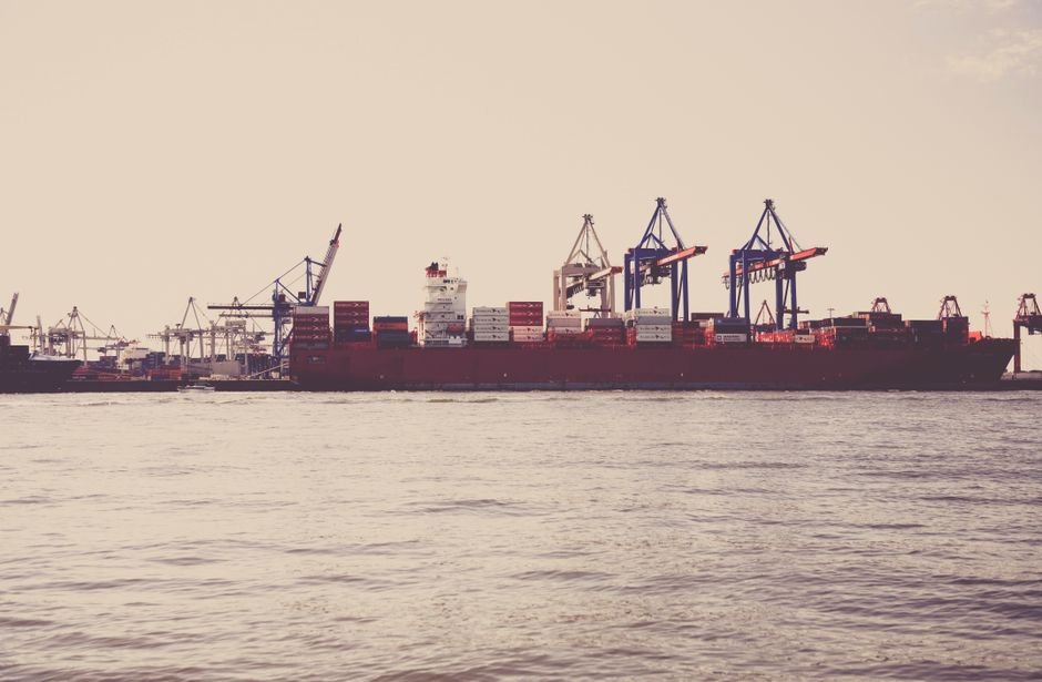 international ecommerce expansion — A cargo ship loaded with containers docked at a seaport under clear skies.