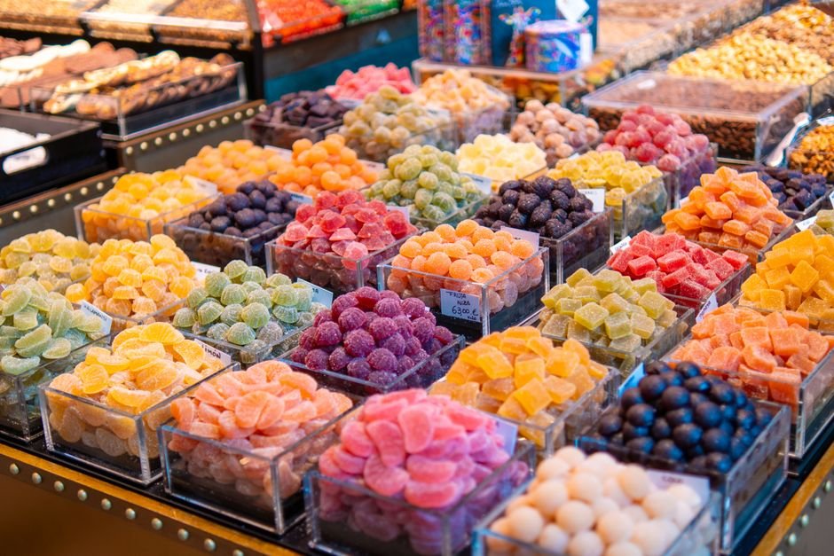Colorful gummy candies arranged in baskets at a vibrant market stall, showcasing sweets.