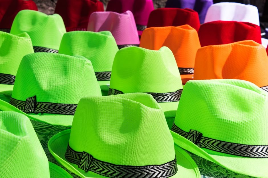 A vibrant assortment of colorful fedora hats arranged in a sunlit display.