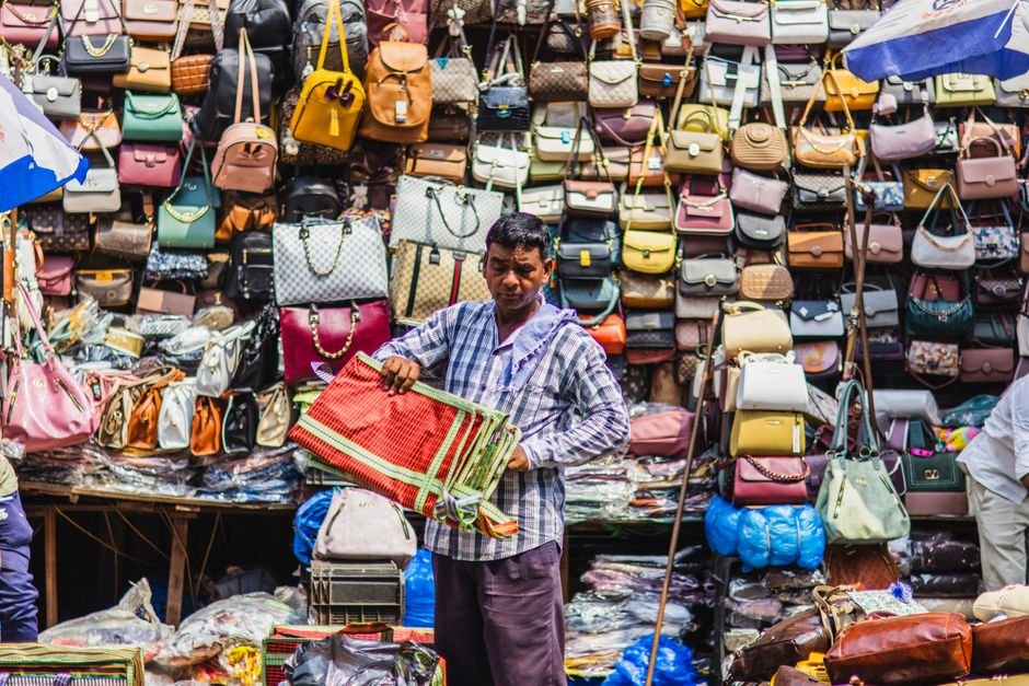 marketplace development — marketplace development — A street vendor showcases a variety of handbags at a bustling market in Kolkata, India.