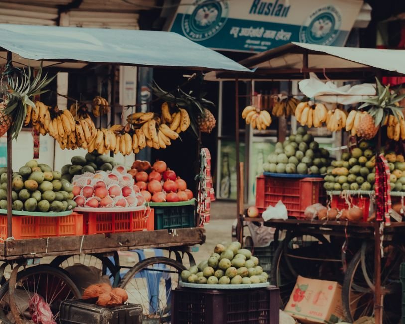 Colorful fruit stand at a vibrant street market in Butwal, showcasing bananas, mangoes, and pomegranates.