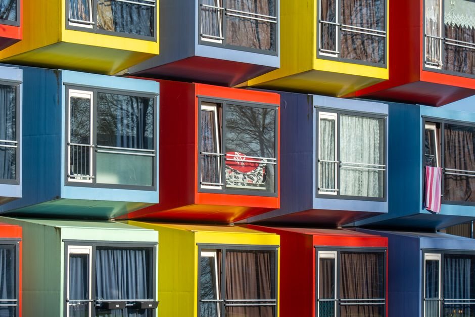 Vibrant stack of modular apartments creating a colorful urban facade in Almere, Netherlands.