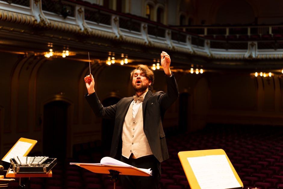 Orchestra conductor passionately leading a performance in an elegant concert hall.